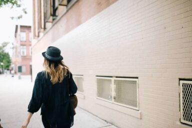 A woman with a stylish hat walks down the street, showcasing how well she's coping with symptoms of ADHD in women.