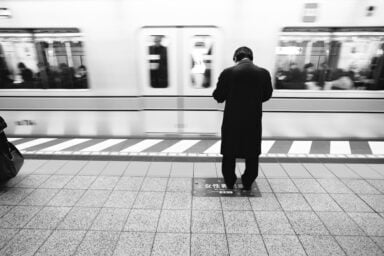 A man stands alone in a subway station in front of a crowded train highlighting the nature of high-functioning depression