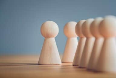 A row of wooden figurines arranged neatly, showcasing orderliness and craftsmanship, illustrating symptoms of obsessive-compulsive personality disorder (OCPD).